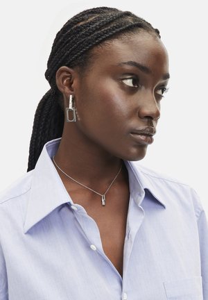 Zilveren geometrische oorbellen hebben een rechthoekig ontwerp met een gestructureerde accent. Een bijpassende zilveren ketting met twee verticale hangers.