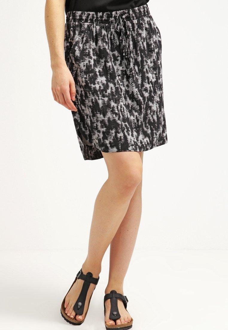 Černo-bílá vzorovaná sukně ke kolenům s elastickým pasem a šňůrkou, doplněná černými žabkami.