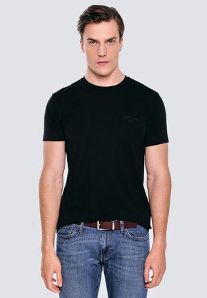 Czarny t-shirt z krótkim rękawem, okrągłym dekoltem i subtelnym detalem logo, połączony z niebieskimi dżinsami i brązowym paskiem.