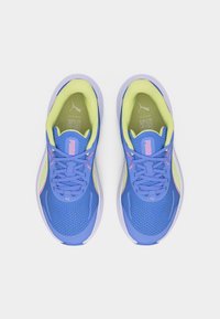 Ζευγάρι από μπλε και λαχανί αθλητικά παπούτσια Puma με ροζ λεπτομέρειες, θέα από πάνω σε λευκό φόντο.