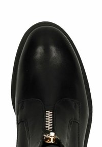 Stivale alla caviglia in pelle nera con punta rotonda, dotato di una zip argentata e cuciture minime ai lati. Texture liscia.