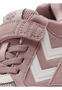 Rosa Sportschuh aus Mesh- und Wildledermaterialien, mit einem Klettverschluss, strukturierten Schnüren und weißen Chevron-Akzenten an der Seite.