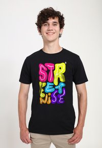 Černé tričko s barevným textem ve stylu bublinek, který říká "STREETWISE" v růžové, žluté, modré, oranžové a fialové barvě. Krátké rukávy, kulatý výstřih.