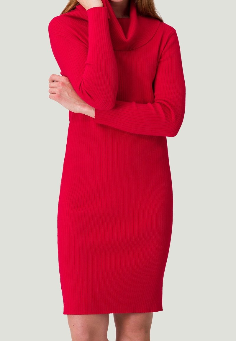 Robe tricotée rouge à côtes avec un col bénitier, des manches longues et une silhouette ajustée. Texture lisse et design longueur genou.