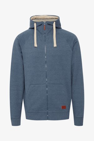Hřejivá mikina s kapucí na zip v tmavě modré barvě, vyrobená z měkké látky, s béžovými tkaničkami, předními kapsami a malou hnědou nášivkou s logem.