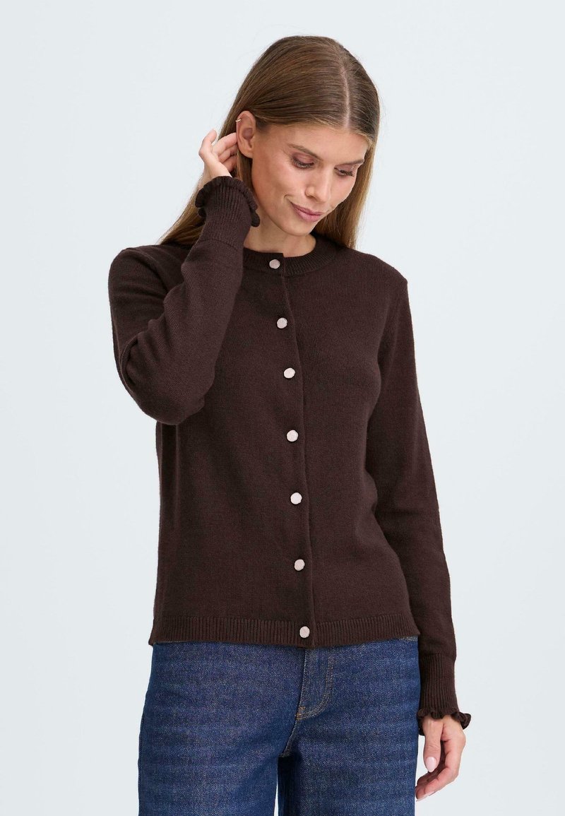 Brauner gestrickter Cardigan mit rundem Halsausschnitt, langen Ärmeln und einer Reihe von sechs großen, hellen Knöpfen auf der Vorderseite.