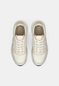 Fehér és bézs sportcipők hálós és nubuk anyagokkal, lekerekített orral, sík fűzőkkel és texturált gumitalppal.