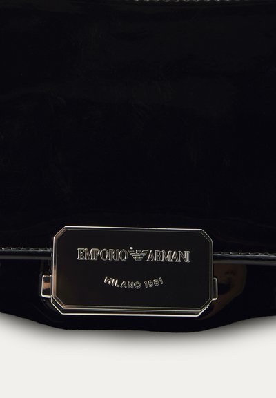 Mustmust mustrahn õmblusnahast käekott, millel on metallmärgis "Emporio Armani Milano 1981" ja stiilne disain. Sile tekstuur ja minimaalne riistvara.
