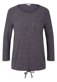Bluza cu mânecă lungă, de culoare mov închis, confecționată dintr-un material moale, având cuvântul "fericit" brodat cu fir argintiu și un șnur ajustabil la margine.