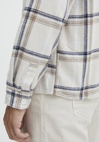 Flanellen shirt met een beige en blauwe ruitpatroon, voorzien van een knoopmanchet en een zijsplit, gemaakt van zachte, gestructureerde stof.