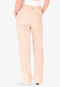 Pantaloni beige a gamba larga con vita elastica. Tessuto liscio e leggero con una vestibilità comoda. Design minimalista, senza motivi visibili.