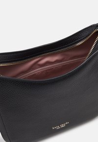 Sort læderhåndtaske med tekstureret overflade, guld lynlås og indvendig foring i pink satin. Har en indvendig lynlås-lomme til organisering.