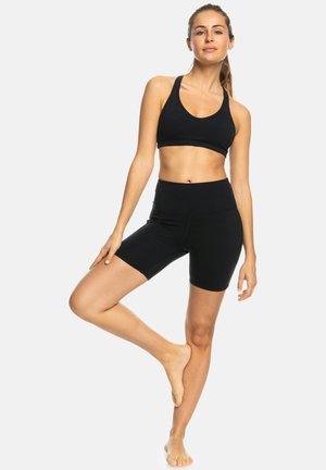 Black sports bra and shorts set, made from stretchy material. Features a fitted design with a high waistband and minimal seams.