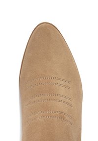 Beżowe zamszowe buty z ostrym noskiem i poziomymi przeszyciami na cholewce. Gładka faktura, o minimalistycznym designie.
