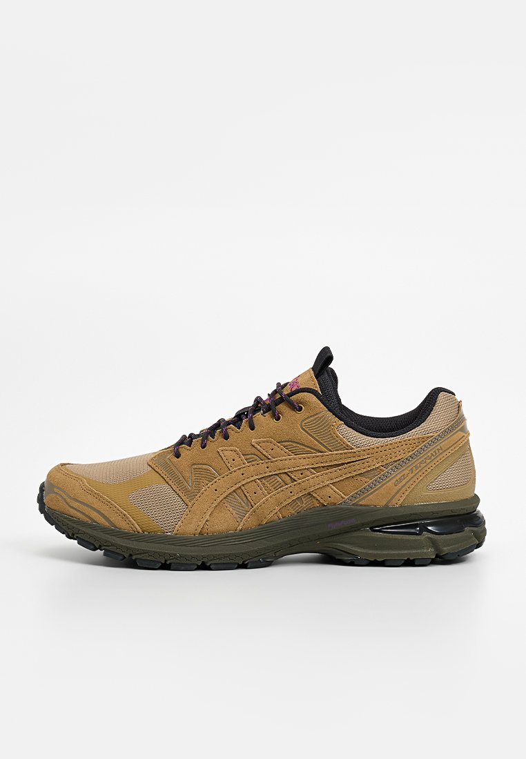 Chaussure de sport marron clair dotée d'un design en mesh et suède respirant, avec des accents noirs, une semelle texturée et des détails violets sur les lacets.