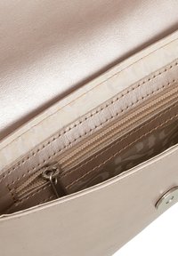 Interno di una borsa color oro rosa metallico che mostra una superficie liscia, una tasca con zip e una fodera a motivo in una tonalità beige chiaro.