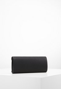 Musta nahkainen clutch, jolla on sileä pinta, sylinterimäinen muoto ja hienovarainen kiilto. Sen muotoilu on saumatonta ilman näkyviä metalliosia.