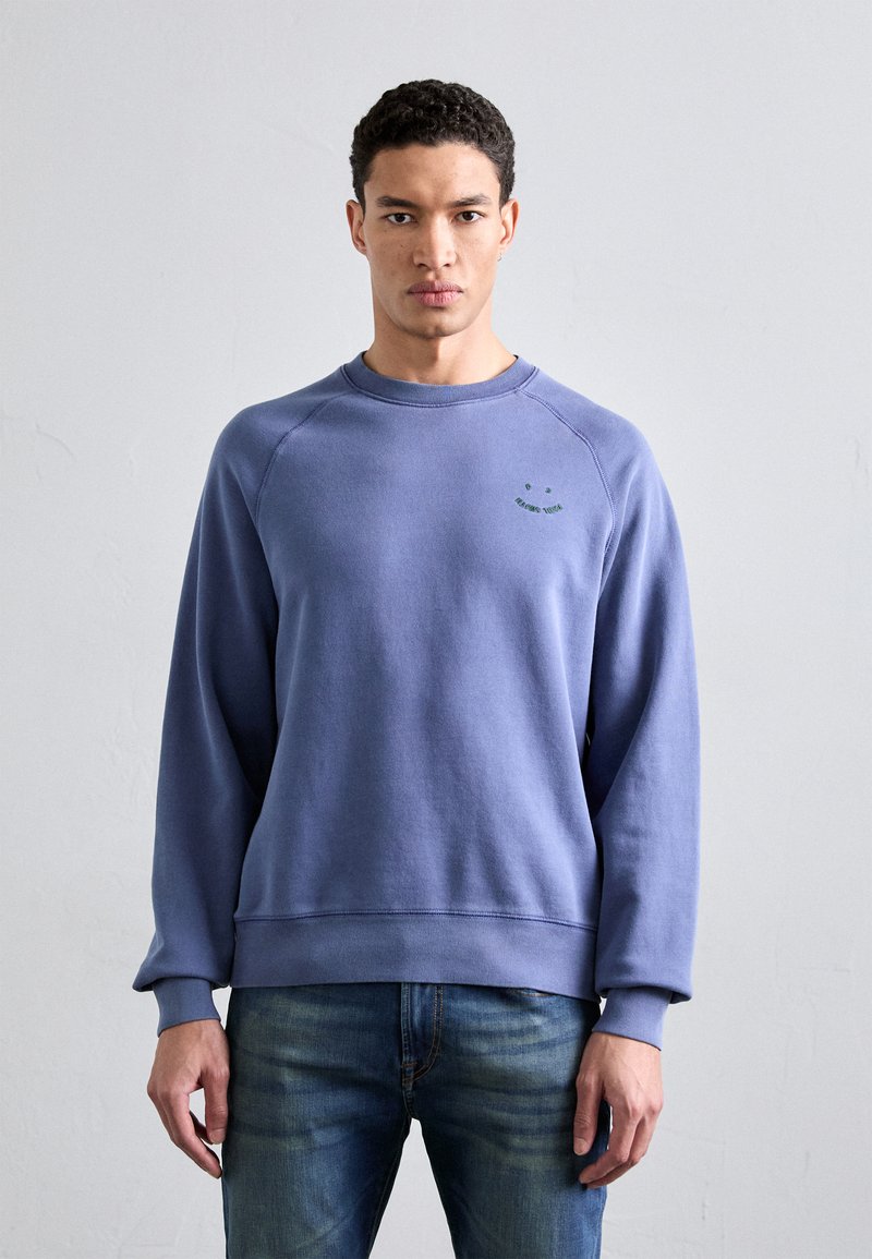 Crew-neck sweatshirt i myk, lys blått stoff. Har ribbede mansjetter og fald, med en liten grønn grafisk detalj på brystet.
