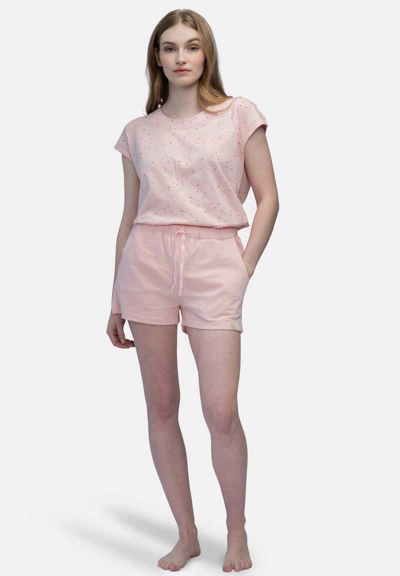 Maglietta rosa con un motivo maculato, abbinata a pantaloni corti rosa coordinati con una cintura elastica e un cordino. Tessuto leggero.