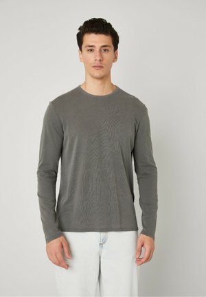 Langærmet skjorte i blødt grå stof, med rund halsudskæring, slim fit og flade sømme. Afsat med lyse jeans.