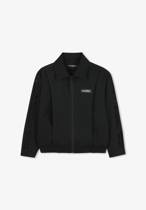 Czarna kurtka z zamkiem z przodu, stójką, elastycznym dołem i mankietami w formie bandażów. Zawiera logo "Karl Lagerfeld" na rękawach.