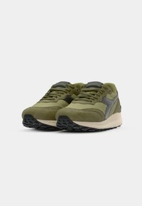 Green athletic shoes featuring a mix of suede and mesh materials, textured sole, and grey accents. Rounded shape with lace-up front.