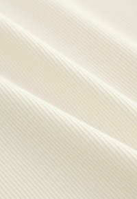 Textured ribbed fabric in soft white, featuring subtle vertical lines and a smooth finish, ideal for clothing or upholstery applications.