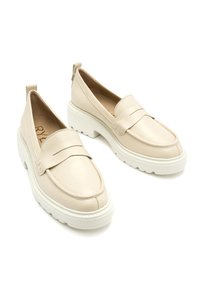 Beige leren loafers met een dikke witte zool, met een ronde neus en een brede band aan de voorkant. Minimale hardwaredetails.