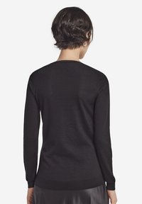 Sort langærmet sweater med rund halsudskæring og ribbet kant og ærmekanter, med en glat tekstur og tætsiddende silhuet.