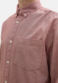 Camicia in chambray rossa con colletto button-down, taschino frontale e bottoni bianchi, realizzata in tessuto testurizzato con un motivo sottile.