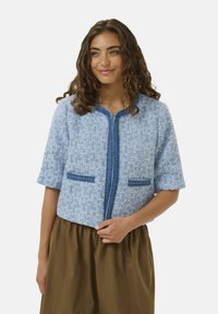 Blaues Tweed-Jacket mit kurzen Ärmeln, offenem Vorderteil, zwei aufgesetzten Taschen mit blauen Akzenten und einer strukturierten, gewebten Oberfläche.