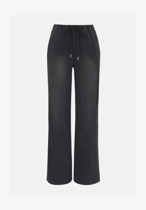 Μαύρο παντελόνι φαρδύ, με ελαστική μέση και κορδόνι, κατασκευασμένο από μαλακό ύφασμα, απεικονίζεται σε απλό φωτεινό φόντο.