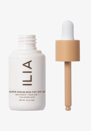 ILIA Super Serum Skin Tint SPF 30 in un flacone bianco con testo marrone; include un contagocce beige con un topo bianco rotondo, 30 ml.