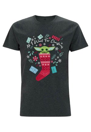 Chemise gris foncé avec un personnage vert qui regarde depuis une chaussette de Noël rouge entourée de cadeaux et de feuillage d'hiver avec le texte « Tout ce que je veux pour Noël ».