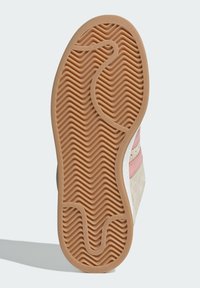 Sneaker sole with a wavy texture, featuring a light brown rubber material and pink accents, designed for traction and durability.