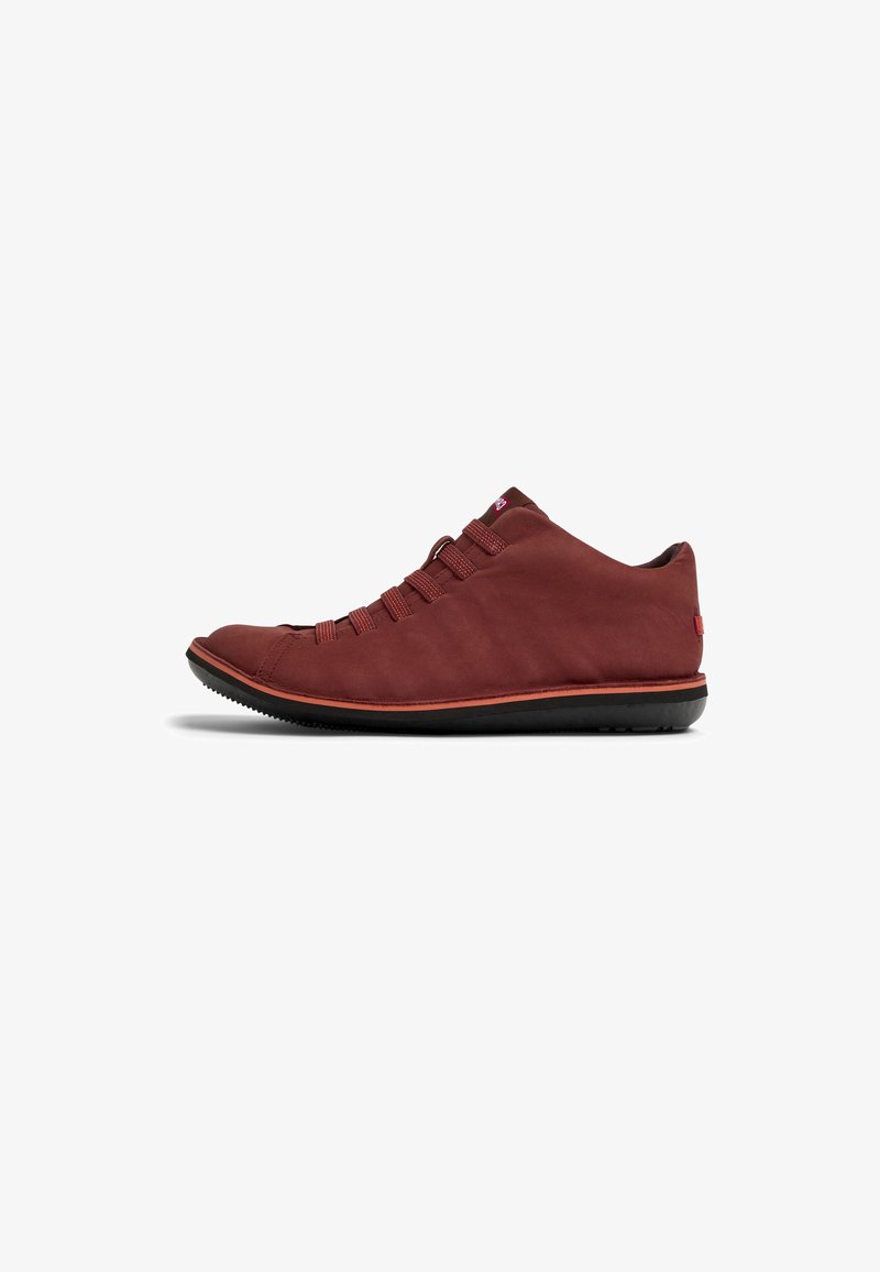 Red leather sneaker with a rounded toe, rubber sole, and elastic lacing. Features a smooth texture and minimalistic design.