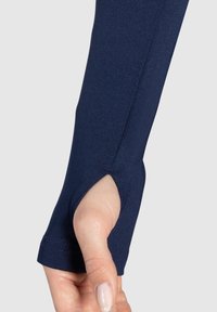 Mörkblå långärmad skjorta med tumhål vid ärmslutet, tillverkad av stretchigt material, som visar en slät yta.