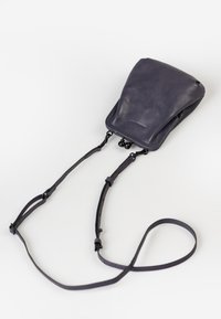 Borsa a tracolla in pelle blu navy con design curvo, spallacci regolabili e dettagli in metallo nero alla chiusura. Texture liscia.