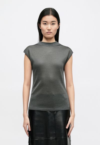 Rövid ujjú, testhez simuló felső sötétszürke texturált anyagból, magas nyakkal, fekete bőrszoknyával párosítva. Minimalista dizájn.