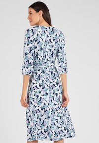 Blumenmuster-Kleid in hellblauen und dunkelblauen Farbtönen. Dreiviertelärmel, taillierte Passform und knielanger Saum. Leichter Stoff mit glatter Textur.