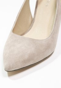 Chaussure plate pour femme en daim beige à bout pointu avec une semelle basse sur fond blanc.