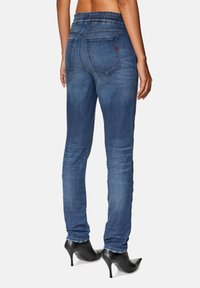 Skinny jeans in dark blue denim with a slim fit. Features a waistband with elastic, two back pockets, and subtle fading details.