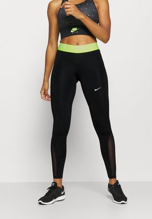 Schwarze Sportleggings mit einem grünen Bund, ausgestattet mit Netzdetails. Ein taillierter Schnitt mit einem kleinen weißen Logo auf dem linken Oberschenkel.