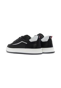 Czarne skórzane sneakersy z białą podeszwą, z szarymi akcentami po bokach i z tyłu. Teksturowana powierzchnia, płaskie sznurówki i minimalistyczny design.