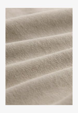Light beige fabric with a textured weave, featuring soft folds that create depth. Smooth surface with subtle variations in tone.