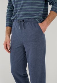 Navyblauwe joggingbroek van zacht materiaal met een elastische tailleband en koord. Zichtbare zijzakken voor extra gemak.