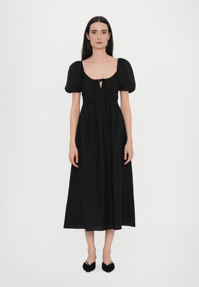 Robe noire midi avec des manches bouffantes, taille cintrée et un détail en trou de serrure au niveau de la poitrine. Texture lisse, tissu léger, ourlet longueur cheville.