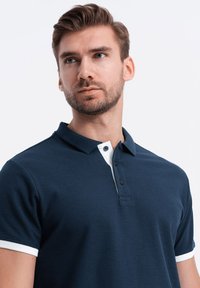 Námornická polokošile ze směsi bavlny s bílým límečkem a akcenty na rukávech. Obsahuje zapínání na tři knoflíky a strukturovanou tkaninu.