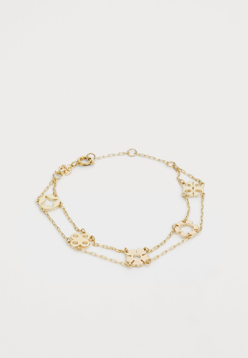 Kuldsest kett-käevõrust, mis sisaldab geomeetrilisi ja lillemotiive, vahelduvaid linke ning lest-klamber sulgemist. Sile metalliline viimistlus.