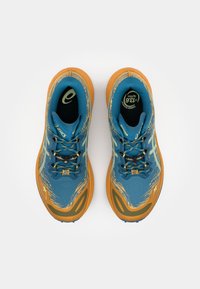Blauwe en oranje sport schoenen met een gestructureerde bovenkant, een gevoerde zool en zwarte veters met gele accenten en logodetails.